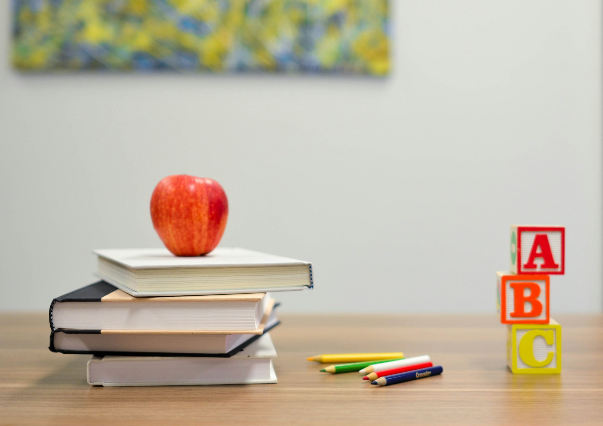 Foto de portada para la publicación "Educar para la Sustentabilidad: un gran desafío", escrita por Óscar Mercado. La imagen muestra una mesa sobre la que hay una pila de 4 libros, lápices de colores y tres pequeños cubos, uno sobre el otro, con las letras A, B y C en orden descendente. Sobre los libros hay una manzana roja.